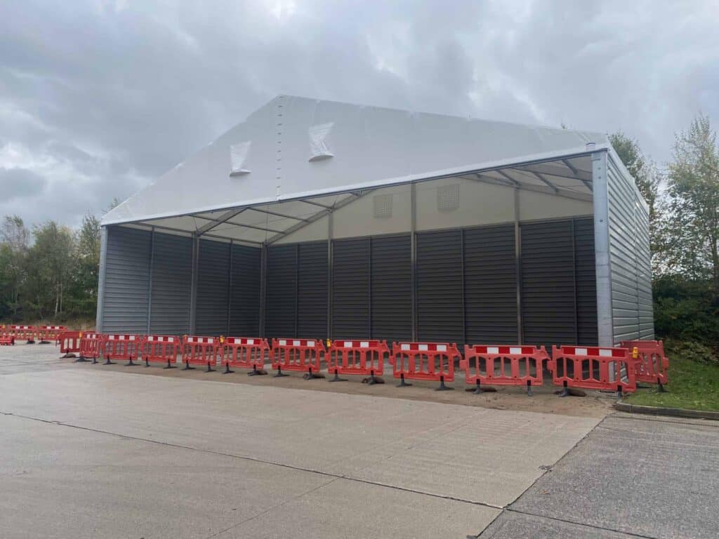 A temporary building canopy with partial enclosure by steel walls.